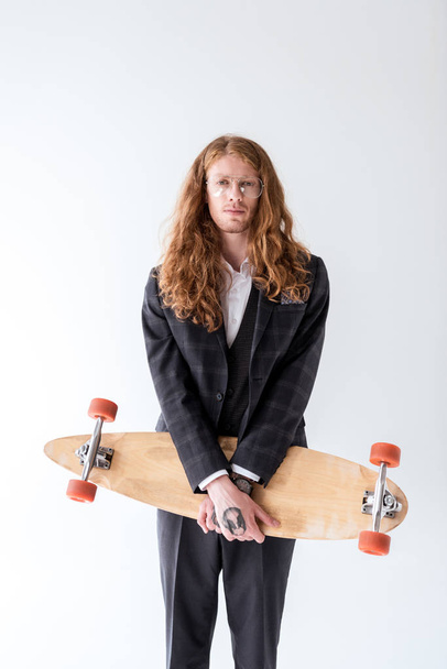 stylish businessman with curly hair holding longboard isolated on white - Foto, Imagen