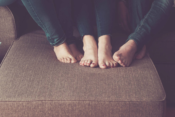 drei Frauen nackte Füße zu Hause auf dem Sofa. Setzen Sie sich hin und bleiben Sie eng mit Freundschaft und Beziehung verbunden. Lesbisches Konzept für pure Liebe und Modernität. - Foto, Bild