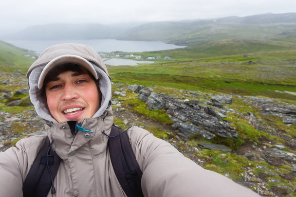 Турист делает селфи на холме возле Скарсвага (возле Нордкаппа). Ориентир Лофотенских островов. Норвегия
. - Фото, изображение