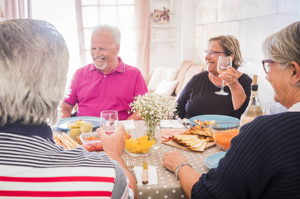 Yaşlı insanlar kıdemli grup birlikte gülen ve having fun peynir, havuç ve Meksika yemeği yemek mutfak kal. Parti ve güzel time.window arka ışık için şarap içmek - Fotoğraf, Görsel