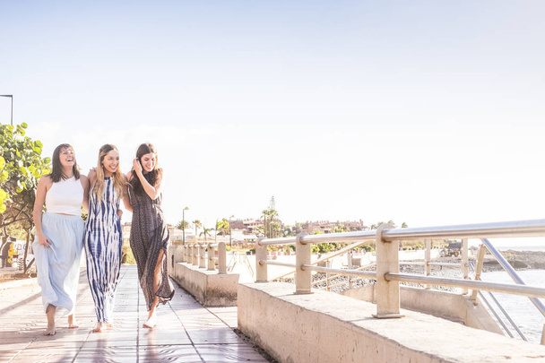 ομορφιά μαζί τρεις νεαρές γυναίκες με τα πόδια στην ομάδα μαζί απολαμβάνοντας το καλοκαίρι στην Τενερίφη. Παραθεριστικές κατοικίες χρόνο γέλιο και το χαμόγελο. - Φωτογραφία, εικόνα