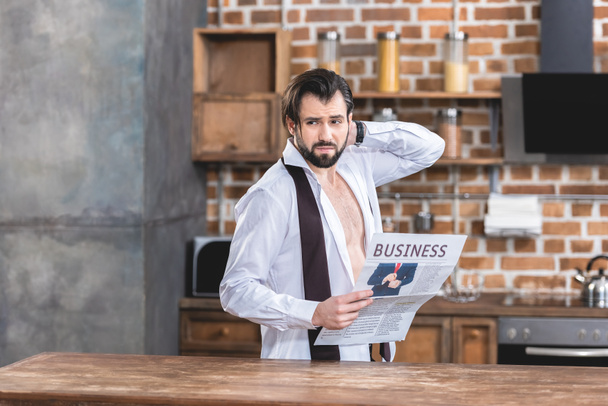 zirytowany samotnikiem przystojny biznesmen trzymając gazetę i patrząc od kuchni - Zdjęcie, obraz