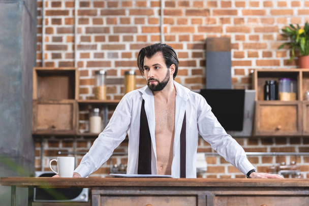 handsome loner businessman standing in unbuttoned shirt at kitchen - Fotografie, Obrázek