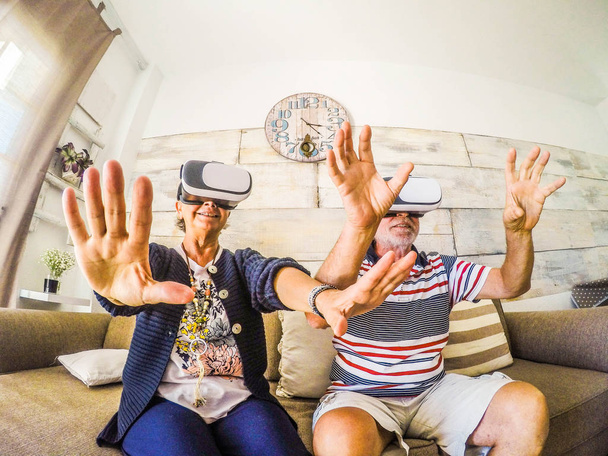 Néhány vezető játék: hullámvasút virtuális-valóság sisak ül a kanapén, otthon. Boldogság a nyugdíjas férfi és nő, goggle-üveg. - Fotó, kép
