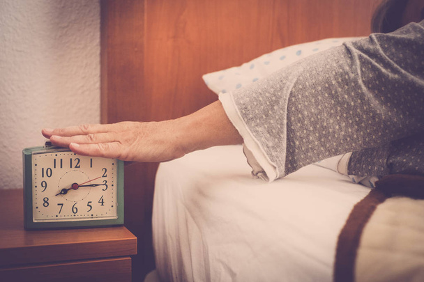 παλιά χέρι ενηλίκων ηλικίας κυρία Σταματήστε τον ήχο αφύπνισης το πρωί να κοιμούνται περισσότερο και πάλι. καθημερινή σκηνή συνταξιούχος τεμπέλης, δεν εργασία έννοιας. - Φωτογραφία, εικόνα