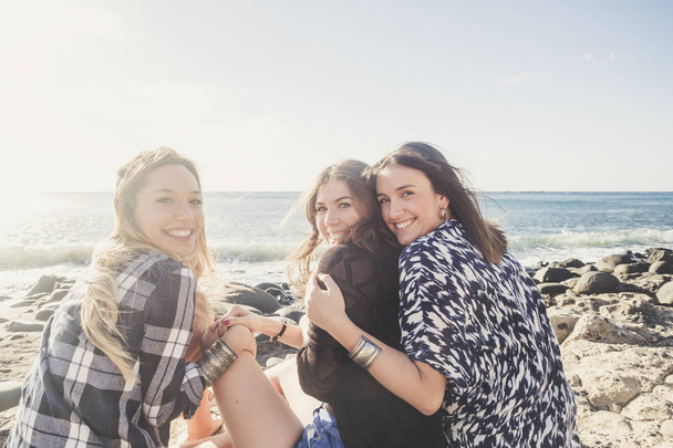 Gruppe schöner junger Frauen, die laut sprechen und lächeln, an einem Steinstrand auf Teneriffa. Mannschaftsmädchen haben gemeinsam Spaß - Foto, Bild