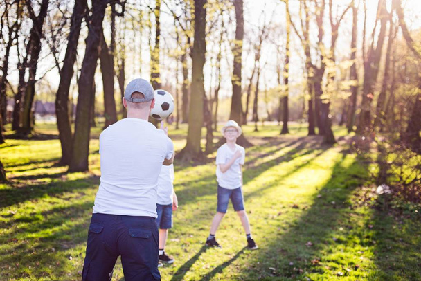 Familia lanzando pelota sobre hierba verde en el parque
. - Foto, imagen