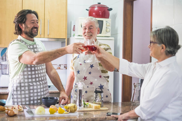 Dégustation en famille de 3 personnes avec du vin rouge lors de la préparation des plats préparés dans la cuisine maison
 - Photo, image