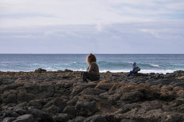 Жінка і чоловік сидять, дивлячись на силу океану в холодну пору року, як зима
 - Фото, зображення