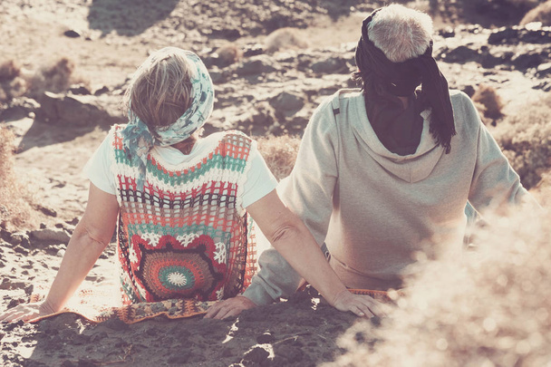 man and woman senior aged grandfathers stay on the rocks feeling the nature, hippy style and vintage filter with colored clothes in sunny day - Фото, изображение