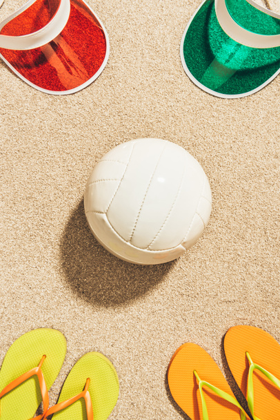 白いバレーボール ボール、カラフルなキャップとフリップフ ロップは砂の上に配置がフラット レイアウト - 写真・画像