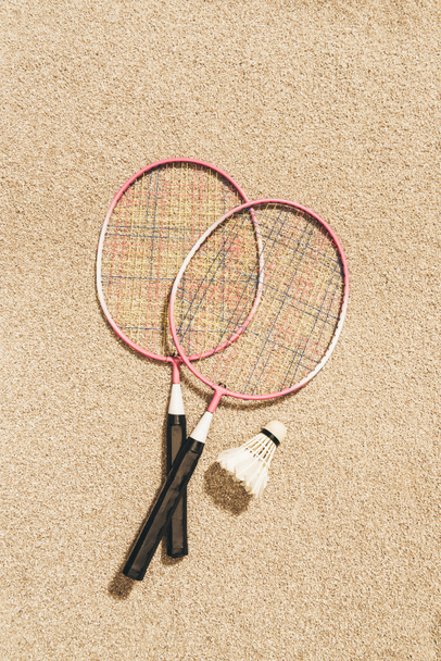 top view of arranged badminton rackets and shuttlecock on sand - Photo, Image