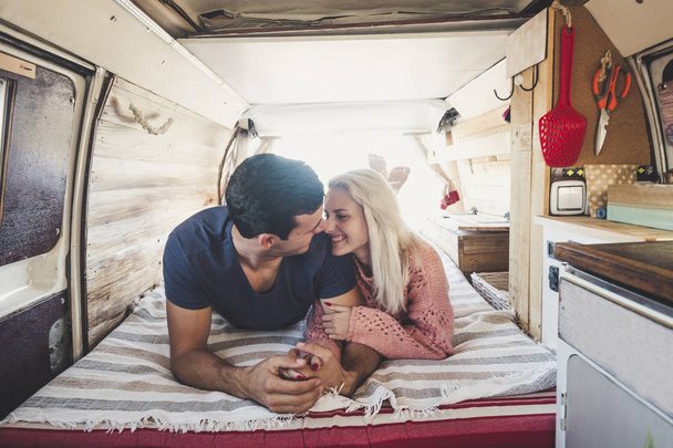 blonde girl and black hair man in love with feeling and passion lay down inside an old vintage restored van for a different lifestyle concept with alternative choice - Foto, Imagem