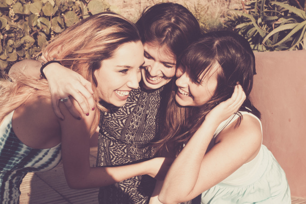 Grupa 25 lat dziewcząt przytulić i śmiać się razem w pracy zespołowej przyjaźń. Słoneczny dzień na wakacje lub wolnego czasu dla grupy. Uroda kobiety. - Zdjęcie, obraz