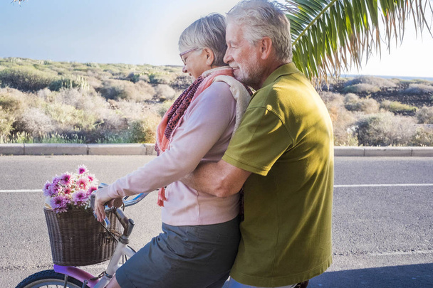 güzel ve sevimli iki yetişkin manken aynı Bisiklet açık oynuyor. boş zaman etkinliği mutlu emekli insanlar için tatil tropikal yerde Okyanusu yakın. Tenerife tatil kavramı ve palmiye ağacı insanlarla gülümseyen - Fotoğraf, Görsel