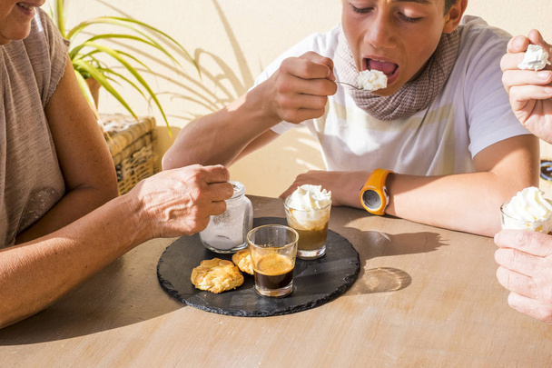 το πρωινό των γενεών. καφές και κρέμα με μπισκότα ad suger. παλιά τα χέρια και το νεαρό αγόρι τρώει. θερινή ώρα. - Φωτογραφία, εικόνα