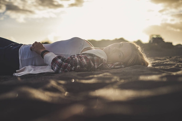wunderschönes Sonnenuntergangslicht für ein nettes blondes Mädchen, das sich am Strand von Teneriffa ausgeruht hat. sie schaut dich an. Im Hintergrund abgestellter Geländewagen - Foto, Bild