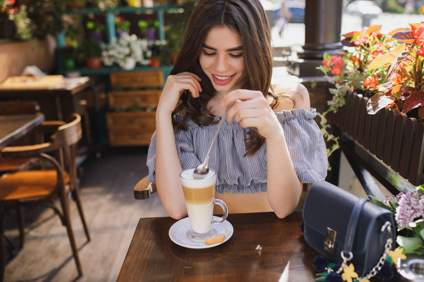 Pretty smiling woman having latte on breakfast in restaurant - Foto, imagen