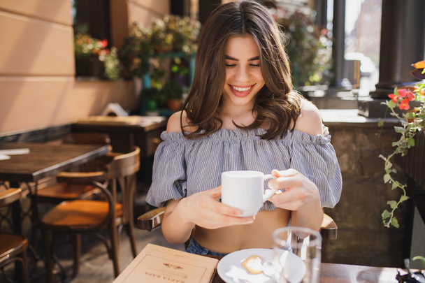 Pretty young woman smiling keeping cup of tea in restaurant - 写真・画像