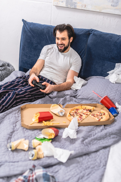 усміхнений чоловік-вчитель грає у відеоігри в спальні
 - Фото, зображення