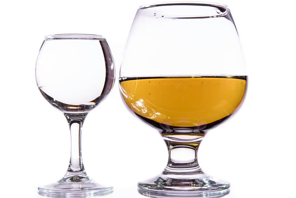 A glass of vodka and a glass of brandy, whiskey or bourbon on a white or colored background - Фото, зображення