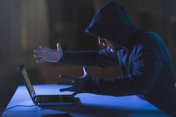 angry hacker with laptop computer in dark room - Фото, зображення