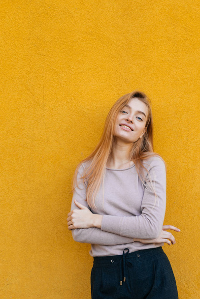 beautiful smiling girl with a blonde model posing against a yellow wall - Foto, Bild