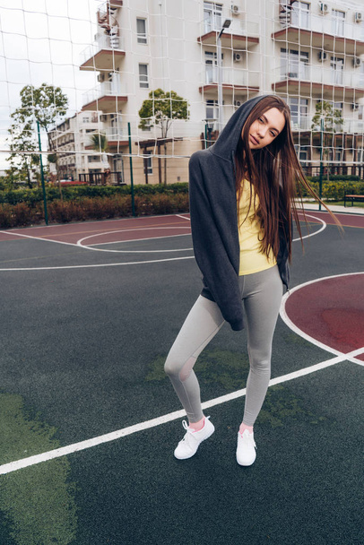 confident slender girl posing on a sports field outdoors, leads an active and healthy lifestyle - Φωτογραφία, εικόνα