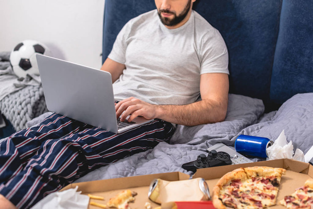 abgeschnittenes Bild eines Einzelgängers mit Laptop im Schlafzimmer - Foto, Bild