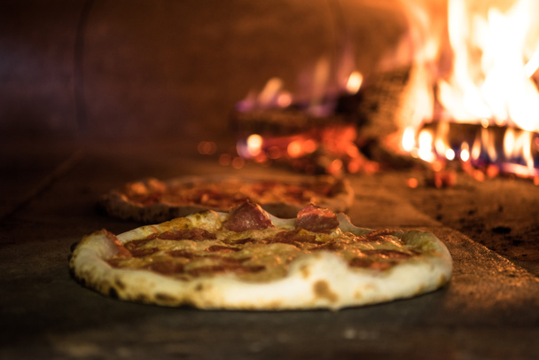 close up view of italian pizza baking in brick oven in restaurant - Foto, afbeelding