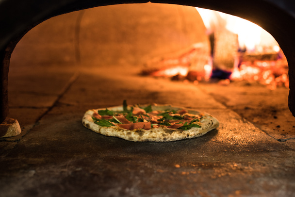 close up view of italian pizza baking in brick oven in restaurant - Foto, afbeelding