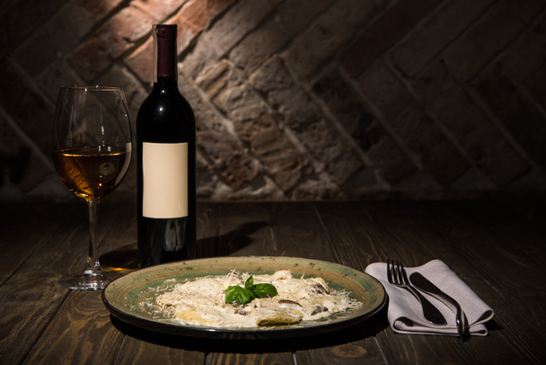 vista de cerca del plato italiano con cubiertos y vino en la superficie de madera
 - Foto, Imagen