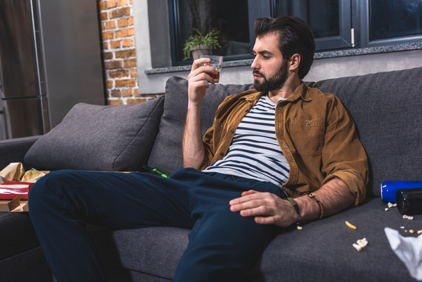 solitario mirando un vaso de whisky en la sala de estar
 - Foto, Imagen