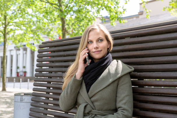 Nuori nainen puistossa penkillä älypuhelimella
 - Valokuva, kuva