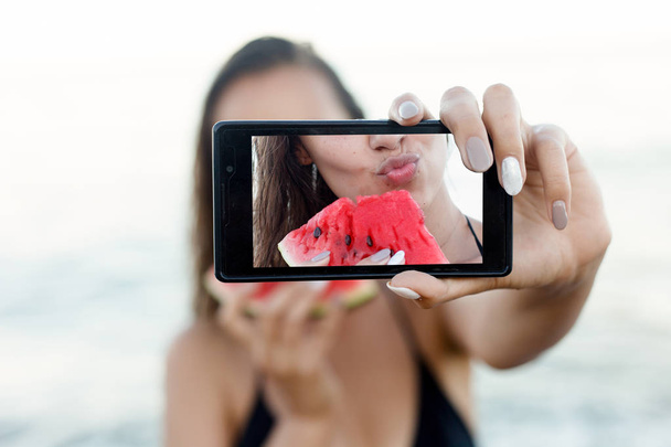 Summer vacation - young girl eating fresh watermelon on sandy beach - Fotografie, Obrázek