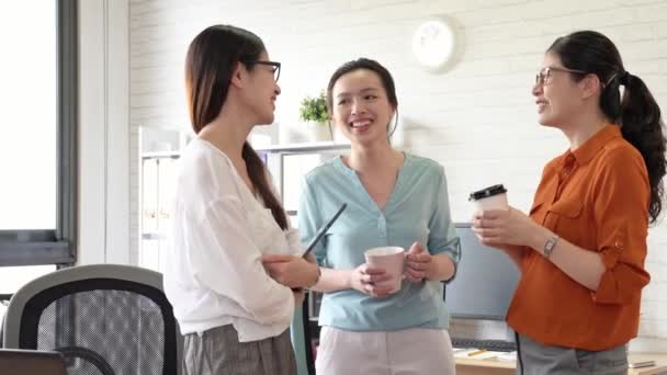three businesswomen enjoy the girls talk in the office and drinking coffee together at afternoon tea break time. - Filmagem, Vídeo
