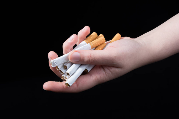 Рука випускає сигарети на чорному тлі
 - Фото, зображення