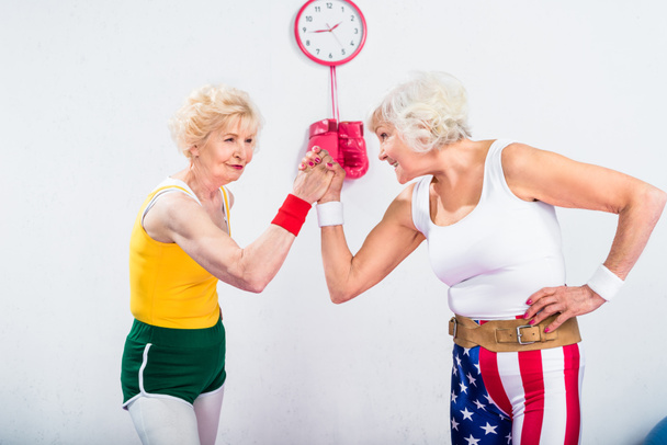 smiling senior sportswomen wrestling and looking at each other in gym - Foto, afbeelding