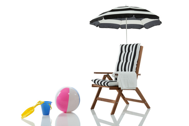 strandstoel met paraplu en strand speelgoed - Foto, afbeelding