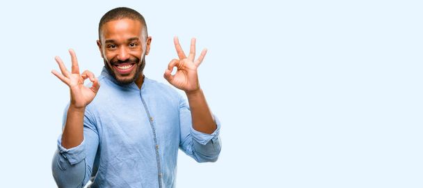 Hombre afroamericano con barba haciendo un gesto de señal aceptable con ambas manos expresando meditación y relajación aisladas sobre fondo azul
 - Foto, Imagen