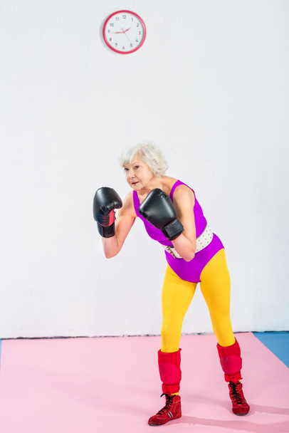 full length view of senior woman in sportswear and boxing gloves training and looking away - Zdjęcie, obraz