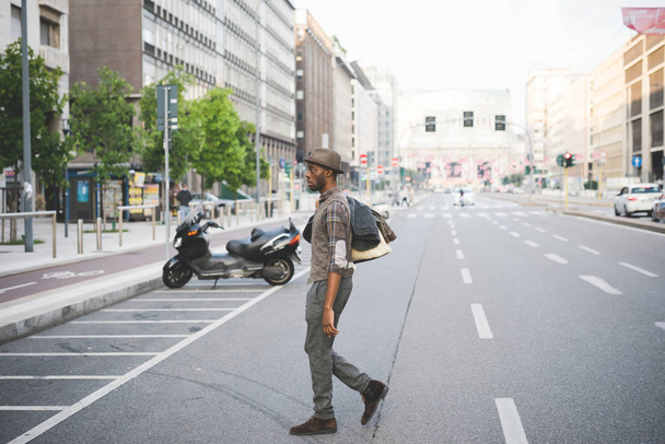 joven hombre africano guapo cruzando la calle en la ciudad
  - Foto, imagen