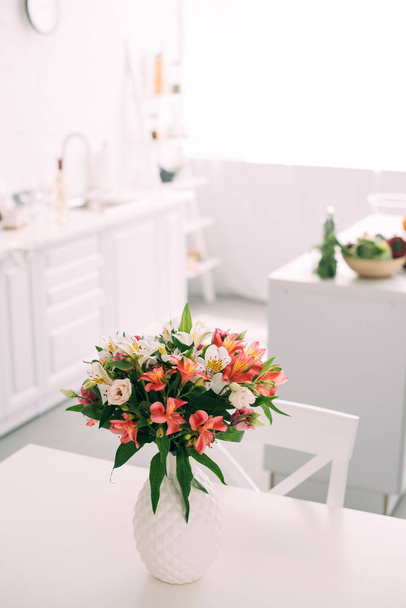 close up view of bouquet of flowers in white vase on table at kitchen  - Photo, Image