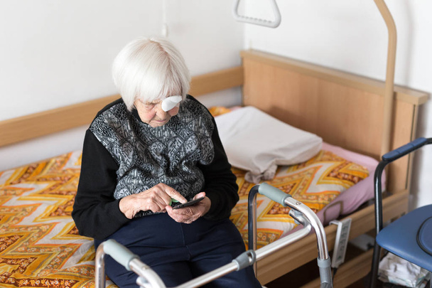 Lonley âgée de 95 ans femme assise à la mauvaise en utilisant un téléphone mobile moderne
. - Photo, image