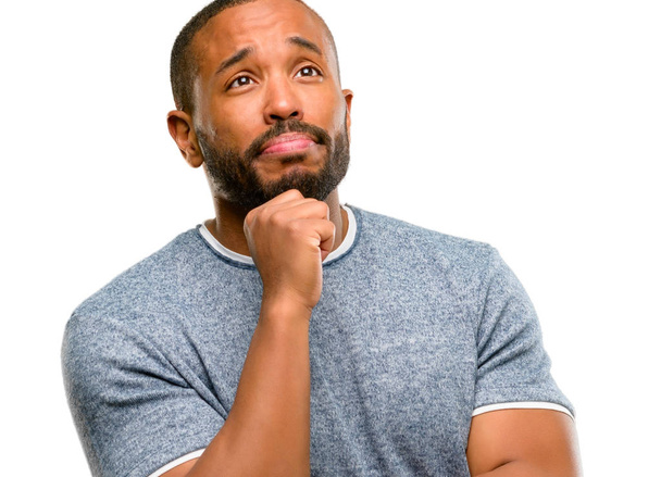 Hombre afroamericano con barba pensando y mirando hacia arriba expresando duda y asombro aislado sobre fondo blanco
 - Foto, Imagen