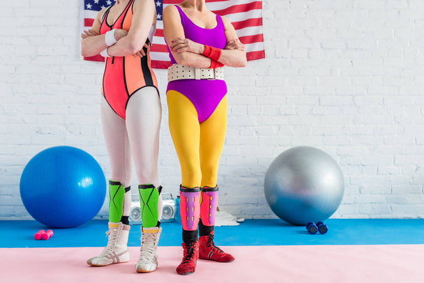 cropped shot of sporty senior women standing with crossed arms near us flag in gym - Photo, Image