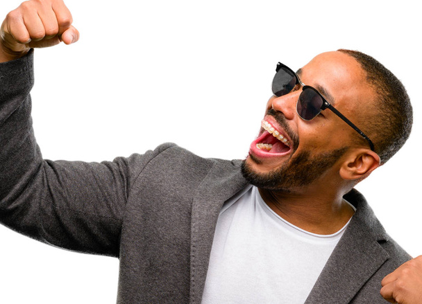 Homem afro-americano com barba feliz e animado celebrando a vitória expressando grande sucesso, poder, energia e emoções positivas. Celebra novo trabalho alegre isolado sobre fundo branco
 - Foto, Imagem