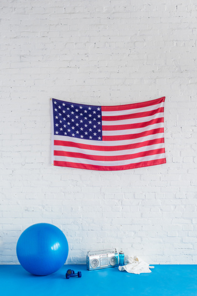 bandera americana, grabadora y equipo deportivo en la pared de ladrillo
 - Foto, imagen