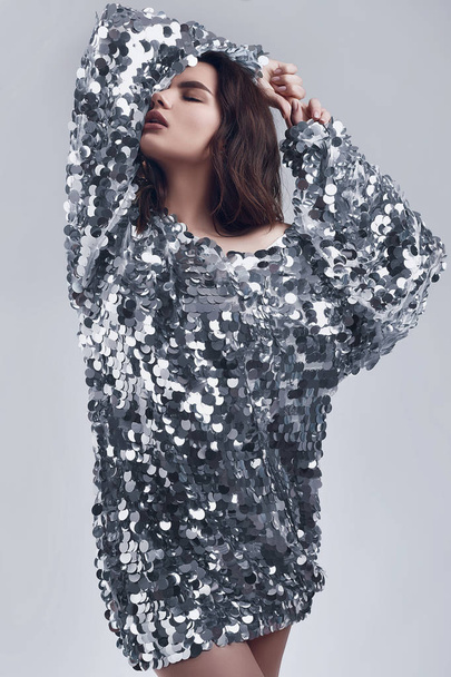 Sensual beautiful brunette woman in a shiny fashion dress of sequins - 写真・画像
