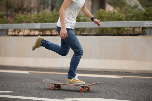 Cropped image of skateboarder sakteboarding on highway - Foto, Imagem